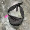 Bolso tipo riñonera con tejido de seda gris con aplicaciones de flores  y interior en tejido de flores de la colección.